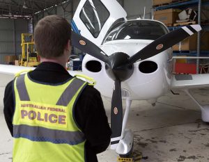 An AFP officer examines a aircraft seized in raids relating to a $165m tax fraud. AFP photo.