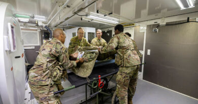 Australian Army officers from 2nd Health Brigade assist United States Army personnel in loading a Japanese Middle Army patient onto a CT machine at the Role 3 field hospital on Exercise Orient Shield 2025 at the Sekiyama Training Area, Japan. Story by Major Diana Jennings. Photos by Lance Corporal Luke Donegan.