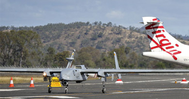 A Heron remotely piloted aircraft arrives at Rockhampton Airport in Queensland in front of a Virgin Australia civilian aircraft.