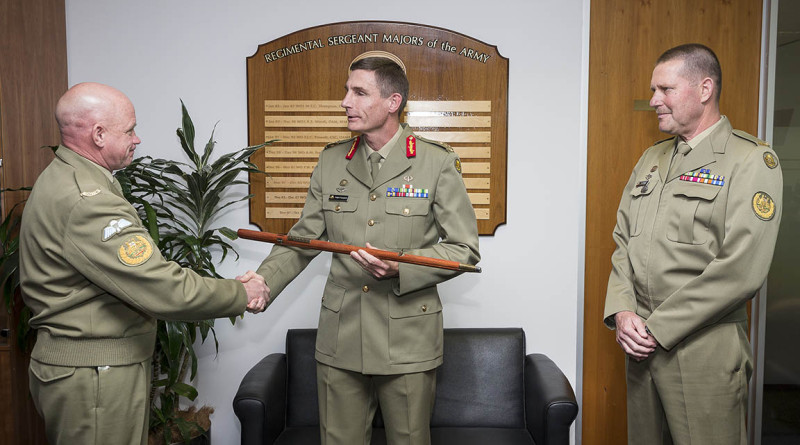 Chief of Army, Lieutenant General Angus Campbell receives the Army Pace Stick from Warrant Officer Dave Ashley at Army Headquarters in Canberra, watched by Warrant Officer Don Spinks