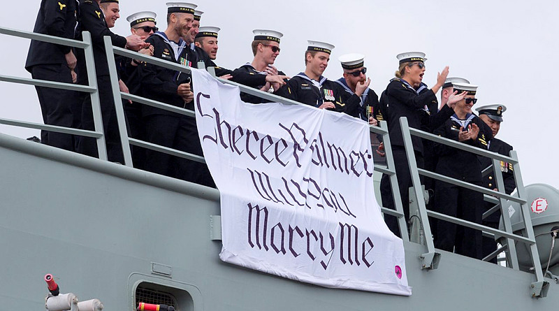 Leading Seaman Aviation Technician Avionics Warwick Douglas, surrounded by his ship mates, displays a banner proposing to his partner who is waiting on the wharf as HMAS Newcastle returns home from a successful rotation in the Middle East. SHE SAID YES! Photo by Able Seaman Tom Gibson