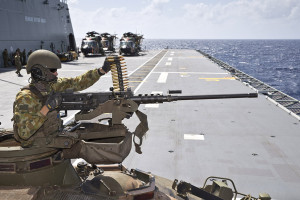 Australian Army soldier Lance Corporal Blake Simington loads a belt fed 50 calibre heavy machine gun on an Australian Light Armoured Vehicle onboard HMAS Canberra's flight deck, during Exercise Sea Raider.