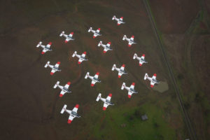 Above: Sixteen Pacific Aerospace CT-4B Airtrainers from the Basic Flying Training School fly in formation over Tamworth. Main Photo: Lieutenant Commander Andrew Kidd, a qualified flying instructor at the ADF Basic Flying Training School, follows the formation, Photos by Corporal Ollie Carter