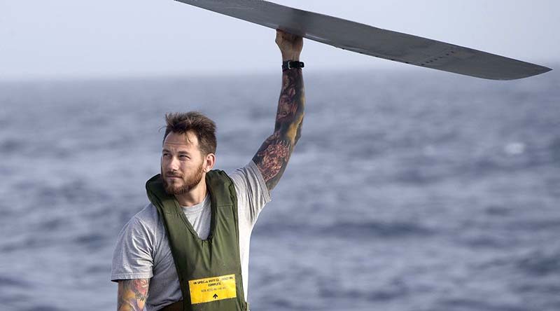 Able Seaman Aviation Technician Aircraft Luke Bacchus spreads the propeller blades of HMAS Perth's embarked MH-60R helicopter.