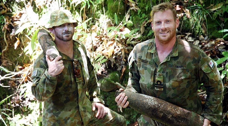 Navy Clearance Divers Petty Officer John Armfield and Lieutenant Robert Kelly carry WWII artillery shells in 'wild country' south of the village of Konga, south-east of Honiara, Solomon Islands.