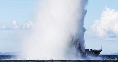 A plume of water dwarfs HMAS Diamantina as a high explosive charge is detonated to remove explosive remnants of war in the Solomon Islands. Photo by Corporal Steve Duncan.