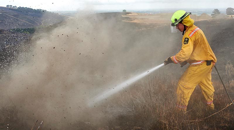 Firefighter Lieutenant Oli Barnfather of the New Zealand Army fights an underground hotspot on the Port Hills of Christchurch. NZDF photo.