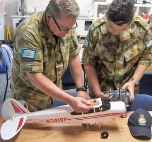 Sergeant (AAFC) Shayne O’Hara instructs Leading Cadet Haralambos Varelias (613 SQN) on binding the transmitter and receiver for a radio-controlled Super Cub aircraft. 