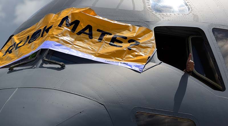 A thumbs up is given as a banner is placed across the front of an Air Force C-17A Globemaster aircraft to show support to mental health awareness on R U OK? Day at RAAF Base Amberley. Photo by Peter Longland.