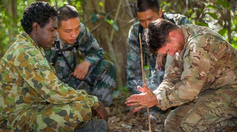 Australian Army soldier Lance Corporal Vinnie Rami (left) guides US Army soldier Sergeant First Class Adam Marques (right) through creating fire using the traditional 'drill' method, while two Chinese soldiers look and learn, during Exercise Kowari 2015 in the Daly River region, Northern Territory, Australia. Photo by Lance Corporal Kyle Jenner.