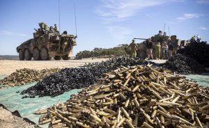 Rheinmetall Boxer CRV (left) prepares for another live-fire at Puckapunyal, while Defence members talk to BAE Systems Australia reps about the Patria AMV35 (right). Photo by Corporal Sebastian Beurich.