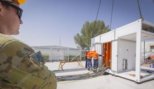 FIT-31 logistics officer Lieutenant Ben Carruthers watches as Datapod employees prepare power cabling for the new Containerised Data Centre at Camp Baird.