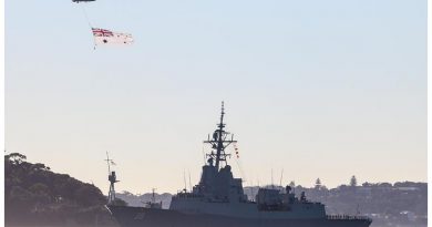 A Royal Australian Navy S-70B-2 Seahawk Helicopter flies the Australian White Ensign over NUSHIP Hobart as she sails past the HMAS Sydney I memorial for the first time. Photo by Petty Officer Kelvin Hockey.