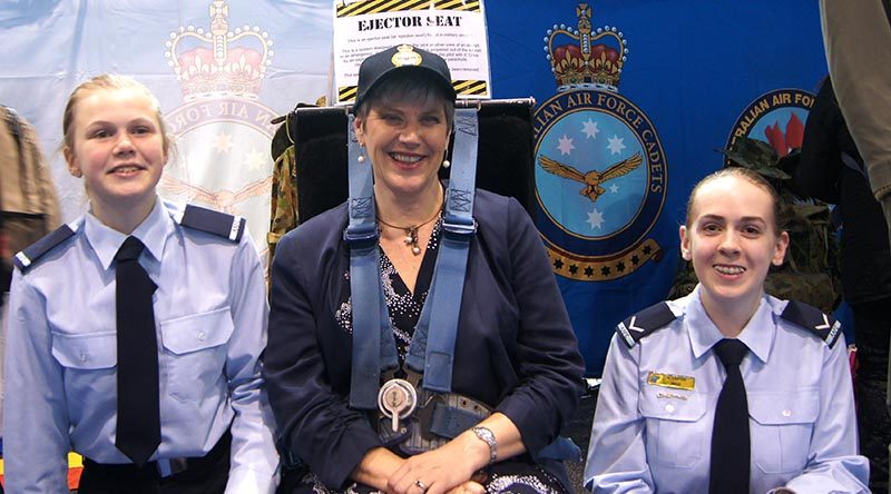 Principal of Urrbrae Agricultural High School Joslyn Fox strapped in to an ejector seat, attended by Cadet Jade Curwood (left) and Leading Cadet Ainsley Carter. Image by Flying Officer (AAFC) Paul Rosenzweig.