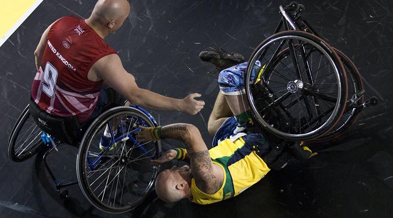 Former soldier Jeff Wright is assisted after a fall in a wheelchair basketball pool match against Denmark. Photo by Corporal Mark Doran.