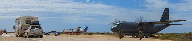 Traffic passes a C-27J Spartan from No 35 Squadron and a Royal Flying Doctors Service Pilatus PC-12, at the Chadwick Roadstrip – one of two designated emergency road landing strips along the Eyre Highway, Nullabor Plains, South Australia. Photo by Corporal David Gibbs.