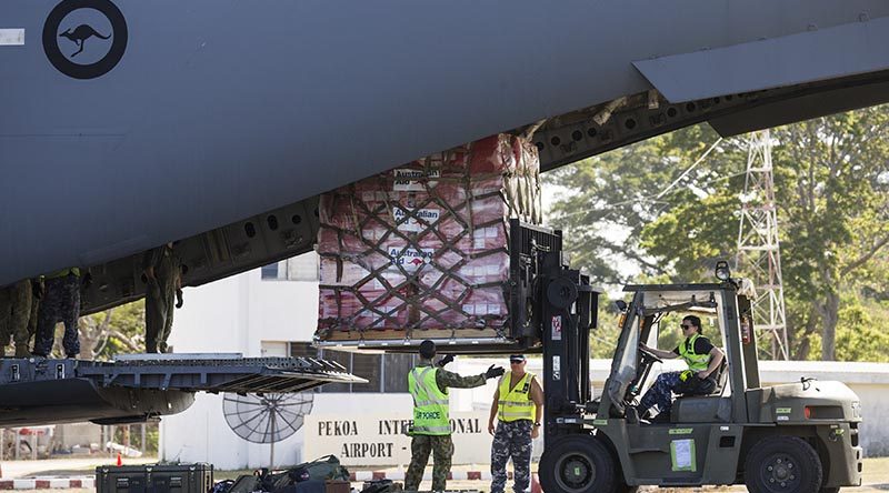 RAAF Sergeant Matt Jones (centre) directs Leading Aircraftwoman Laura Gale as she removes a pallet of Australian Aid supplies from a C-17 Globemaster in Vanuatu during Operation Vanuatu Assist 2017. Photo by Leading Seaman Jake Badior.