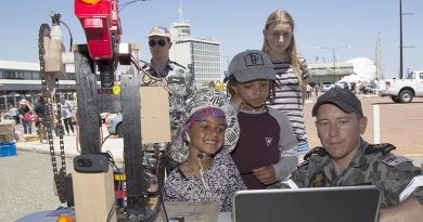 Petty Officer Chris White shows Akosua and Kk an auto targeting Nerf gun created for a robotics competition at the HMAS Stirling Fleet Support Unit-West display, during the Port of Fremantle Maritime Day held on Victoria Quay in Fremantle. Leading Seaman Bradley Darrell.