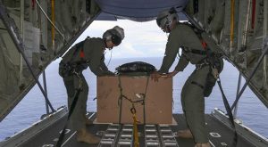 Royal Australian Air Force Sergeant Karl Penny, left, and Warrant Officer Nicholas Stubbs-Race, 37 Squadron loadmasters, prepare to release a care bundle during Operation Christmas Drop.