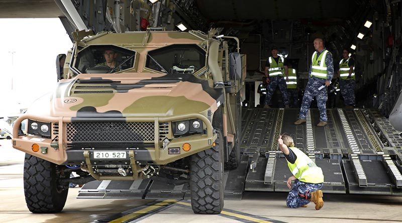 RAAF Base Amberley Air Movements personnel guide Australian Army WO2 James Moss as he reverses a Hawkei into a C-17A Globemaster. Photo by Corporal Ben Dempster.