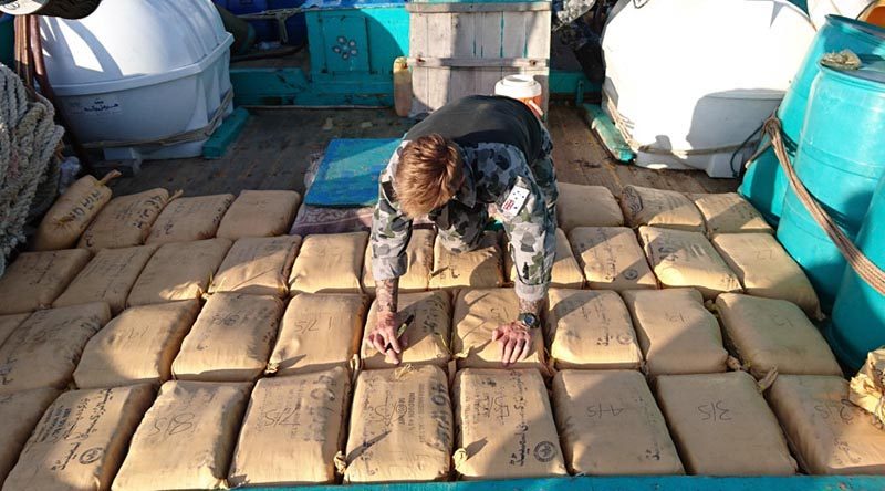 Leading Seaman Clearance Diver Luke Woodcroft from HMAS Warramunga numbers parcels of seized narcotics on the deck of a trafficking vessel. Photo by Leading Seaman Tom Gibson.