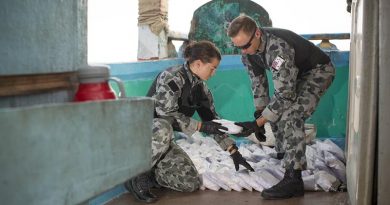Able Seaman Stephanie Pannell passes a bag a seized narcotics to Leading Seaman James Walker during an illicit cargo seizure by HMAS Warramunga in the Middle East. Photo by Leading Seaman Tom Gibson.
