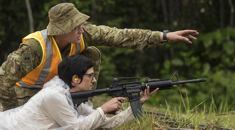 Australian Army officer Lieutenant Patrick Ingram supervises his civilian employer, Anita Gordon, as she prepares to fire an M4 carbine during Exercise Boss Lift in Malaysia. Photo by Sergeant Janine Fabre.