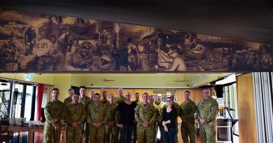 Artists Rob Douma and Kelly Bianchi pose beneath their mural with Chauvel Sergeants' Mess PMC WO1 Brent Doyle and other members of the Mess Committee.