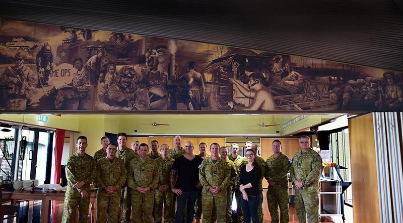 Artists Rob Douma and Kelly Bianchi pose beneath their mural with Chauvel Sergeants' Mess PMC WO1 Brent Doyle and other members of the Mess Committee.