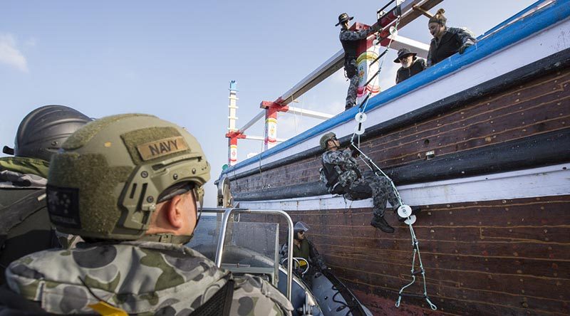 HMAS Warramunga boarding team member Able Seaman Aaron Richardson climbs onto a vessel of interest. Photo by Leading Seaman Tom Gibson.