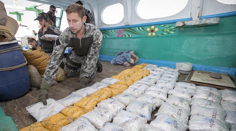 A sailor from Royal Australian Navy ship HMAS Warramunga prepares to remove packages of heroin from a dhow during a boarding operation. Photo by Leading Seaman Tom Gibson.