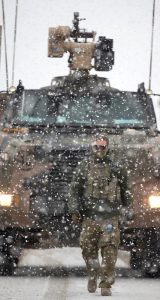 An Australian Army Force Protection Element soldier guides a Protected Mobility Vehicle Bushmaster out of Camp Qargha for task at the Afghan National Army Officer Academy.