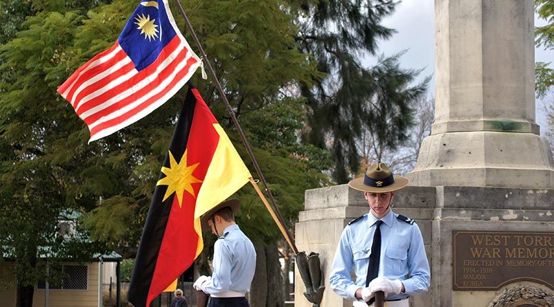 Australian Air Force Cadets CCPL Levi Schubert and CCPL Simon Russell from 604 Squadron Rest on Arms Reversed under the flags of Malaysia and Sarawak. Photo by Flying Officer (AAFC) Paul Rosenzweig