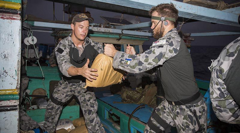 HMAS Warramunga boarding party members Able Seaman Corey Bartlett and Able Seaman Jacob Dun relocate parcels of seized narcotics. Photo by Leading Seaman Tom Gibson.