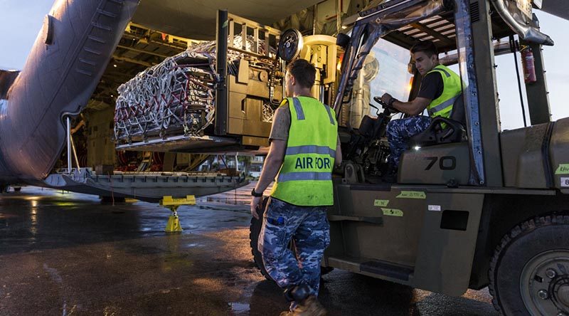 RAAF Corporal Adam Parrington guides Leading Aircraftman Madison Dukes, while loading a C-130J Hercules with humanitarian-aid supplies in Balikpapan as part of Operation Indonesia Assist 2018. Photo by Leading Seaman Jake Badior.