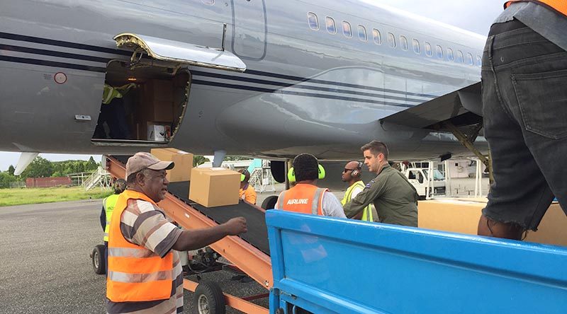 Flight Lieutenant Sam Hatrick, aircraft captain from the Royal New Zealand Air Force’s No.40 Squadron, helps offload about two tonnes of voting equipment and operational supplies for The Fred Hollows Foundation New Zealand from an RNZAF Boeing 757 aircraft at Honiara. NZDF photo.