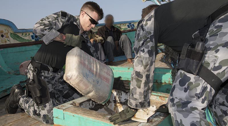 Leading Seaman Aaron Wheeler pulls a sack containing suspected illegal narcotics from the hold in a dhow. Photo by Leading Seaman Bradley Darvill.