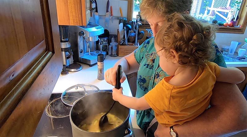 Zoe helps Nana stir Grandad's seafood chowder.