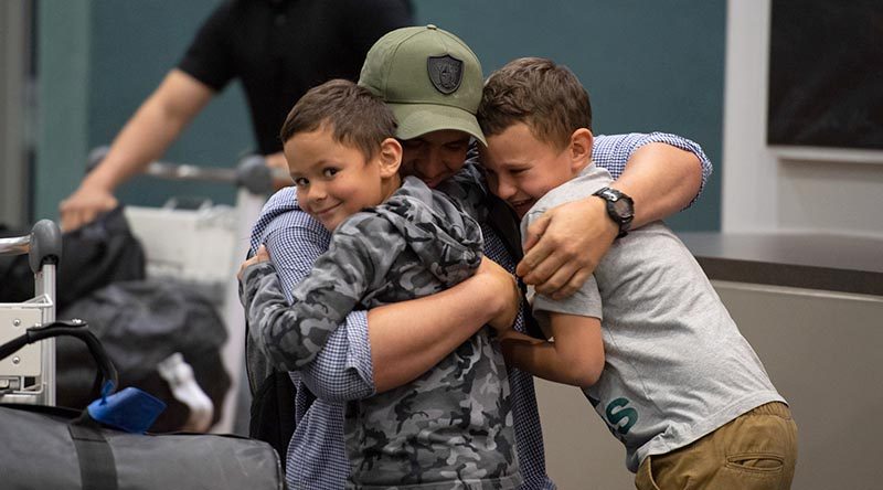 A New Zealand Defence Force soldier returning home after a six-month deployment in Iraq hugs his two sons upon arrival at Royal New Zealand Air Force Base Ohakea this afternoon. NZDF photo.