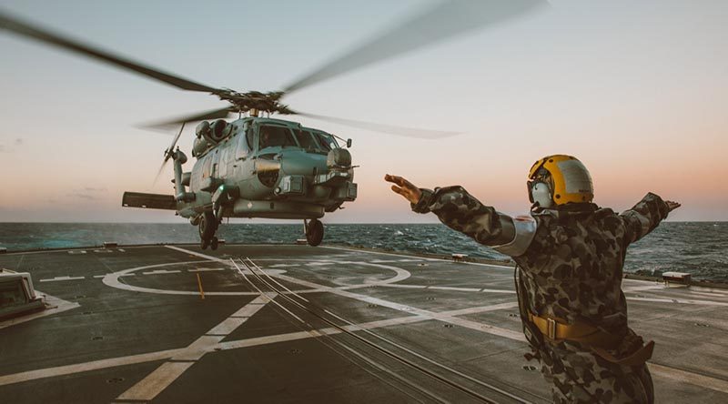 Leading Seaman Christy-Lee Doyle guides an MRH-60R Helicopter onto the flight deck of HMAS Toowoomba during unit readiness training. Photo by Leading Seaman Tara Byrne.