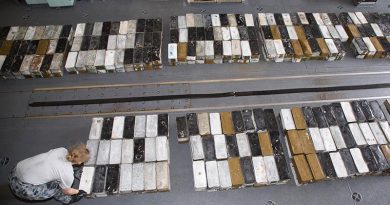 Lieutenant Megan Ryan stacks boxes ammunition seized during a boarding in HMAS Ballarat's hangar. Photo by Leading Seaman Bradley Darvill.