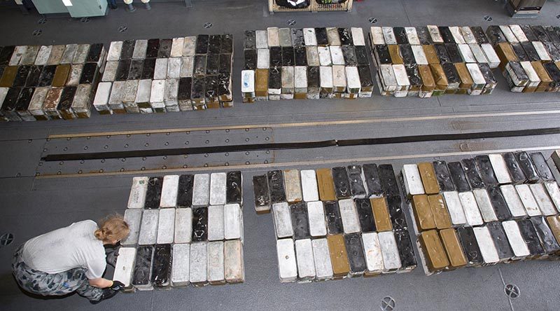 Lieutenant Megan Ryan stacks boxes ammunition seized during a boarding in HMAS Ballarat's hangar. Photo by Leading Seaman Bradley Darvill.