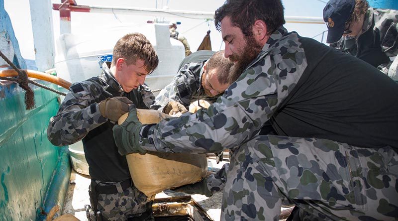 Able Seaman Justin Springer and Leading Seaman Daniel Colliver remove sacks containing suspected narcotics from a dhow's hold in the Middle East. Photo by Leading Seaman Bradley Darvill.