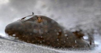 An RAAF C-27J Spartan and its pilot, Flying Officer Oran Harden from 35 Squadron, is reflected in a tarmac puddle at Pohnpei International Airport, Federated States of Micronesia, during Operation Solania. Photo by Gunner Sagi Biderman.