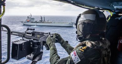 Leading Seaman Jason Griffiths mans the MAG 58 light support weapon in HMAS Stuart's MH-60R helicopter with HMAS Sirius in the background. Photo by Leading Seaman Tara Byrne.