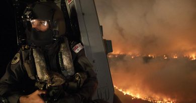 Royal Australian Navy aircrewman Leading Seaman Ben Nixon of 808 Squadron assesses a NSW national-parks bushfire from his MRH90 Taipan helicopter. Photo by Chief Petty Officer Kelvin Hockey.