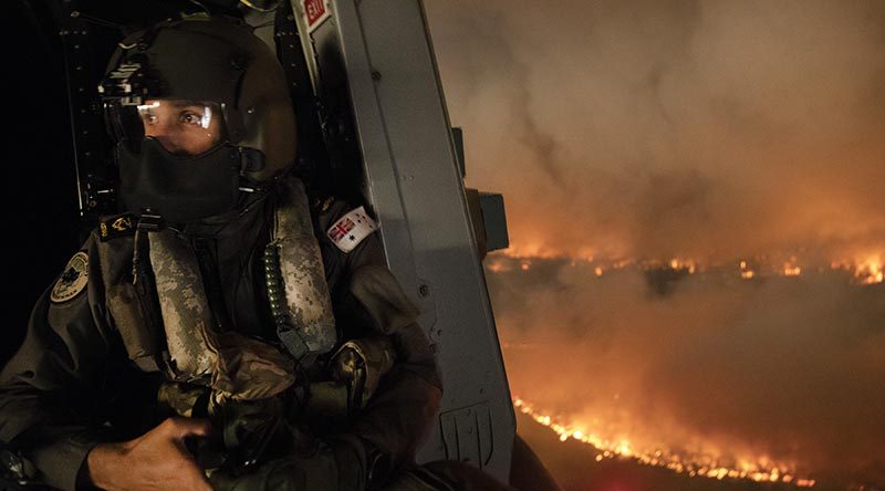 Royal Australian Navy aircrewman Leading Seaman Ben Nixon of 808 Squadron assesses a NSW national-parks bushfire from his MRH90 Taipan helicopter. Photo by Chief Petty Officer Kelvin Hockey.