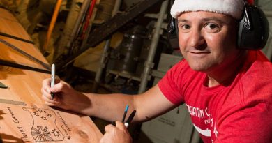 Flight Sergeant Geoff McLaughlin of Number 37 Squadron writes a message on an airdrop load destined for a Micronesian island during Operation Christmas Drop 2019. Photo by Corporal David Said.