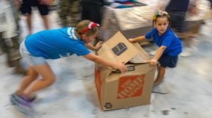 Santa's little OCD helpers slide a box of clothes to a supplies bundle during Operation Christmas Drop 2019 preparations. US Air Force photo by Staff Sergeant Kyle Johnson.