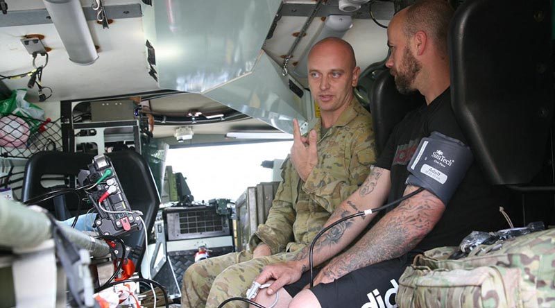 Private Brenden Walker, in a Bushmaster ambulance, gives Jay Twemlow a check-up during a health visit to Batlow, NSW. Photo by Major Cameron Jamieson.